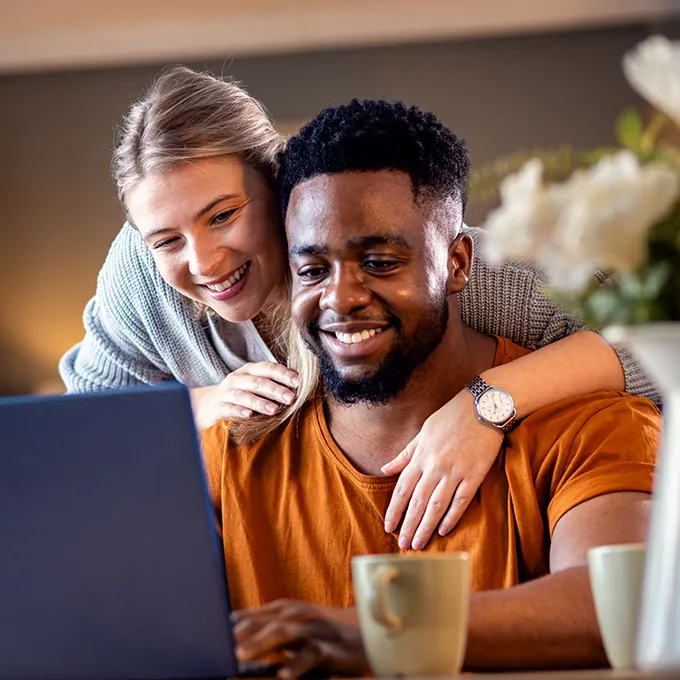 Happy couple looking at laptop at home